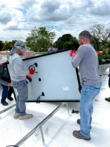 rabajadores levantando un panel solar en posición vertical en la estructura de montaje en el techo.