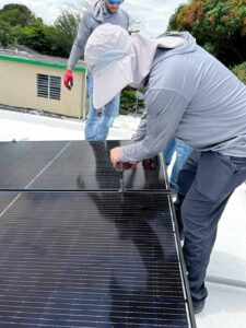 Dos trabajadores instalando paneles solares en un techo.