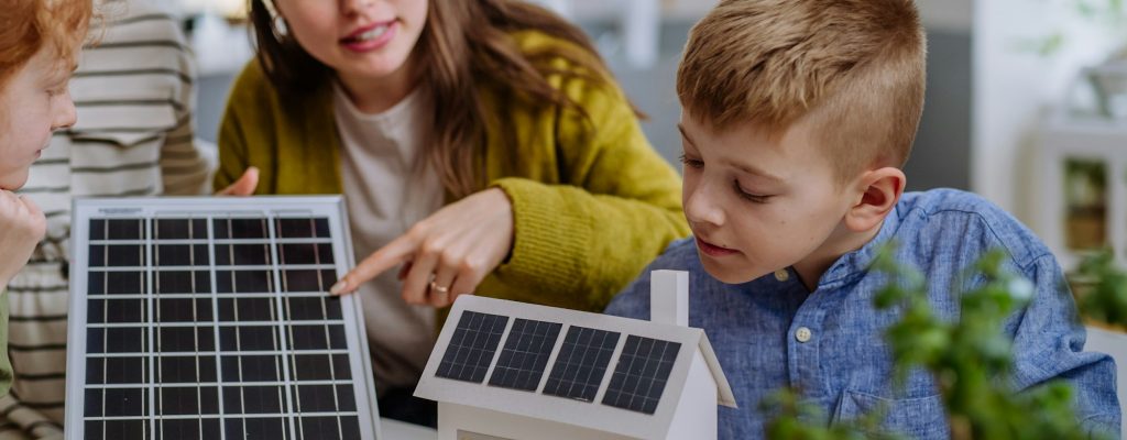 Familia explorando la instalación de paneles solares en una maqueta de casa